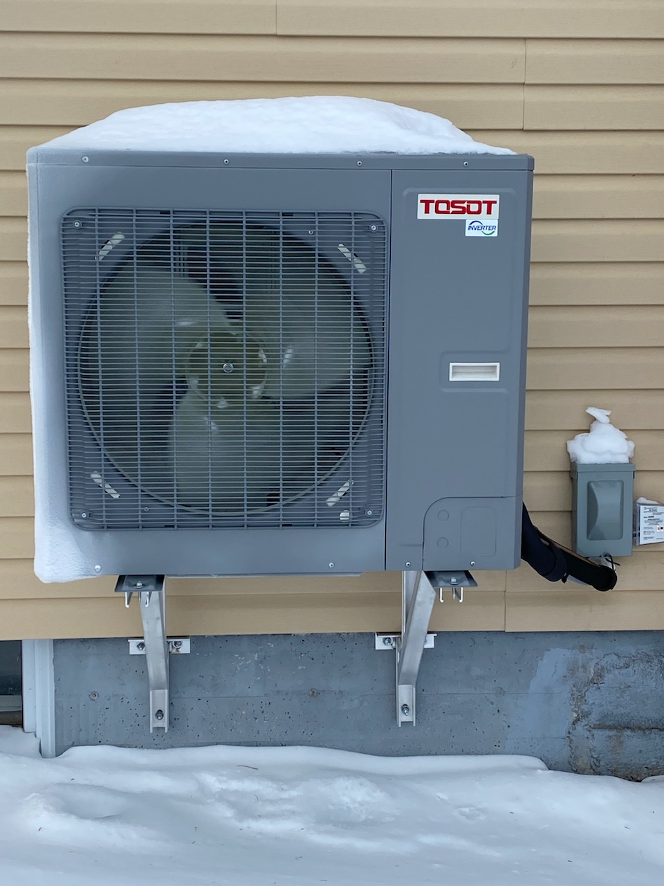 heat pump condenser covered in snow during winter conditions